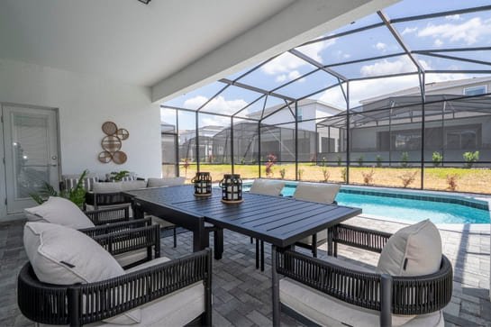 Área externa moderna com mesa de jantar, cadeiras confortáveis e piscina, criando um espaço perfeito para relaxamento e convivência.